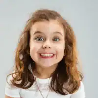 Smiling girl with curly hair enjoying Petra Play toy.